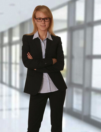 Katrin Hehl im dunklen Blazer mit verschränkten Armen in einem hellen Büroflur